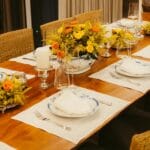 Elegancko nakryty stół z żółtymi i pomarańczowymi kwiatami