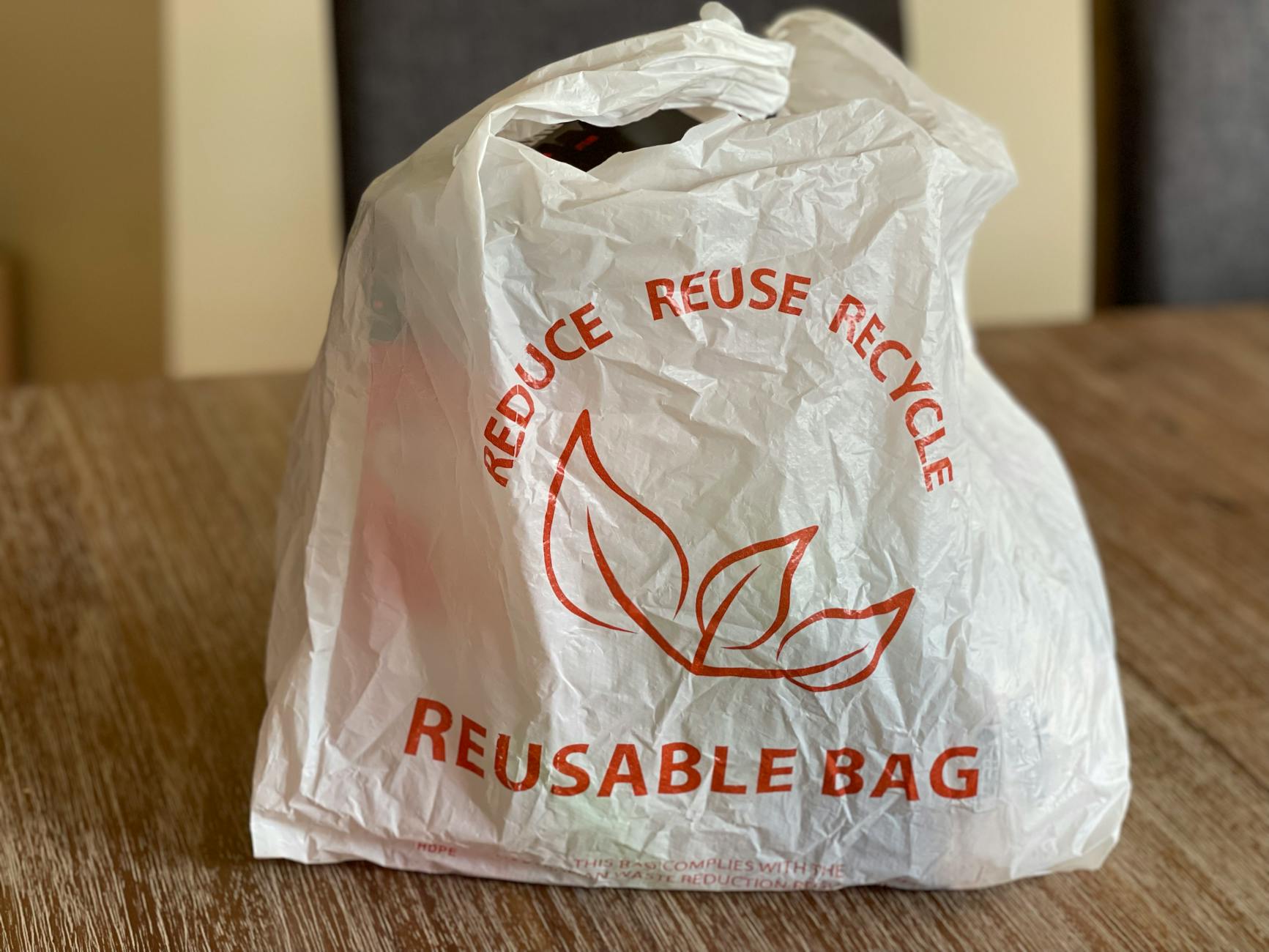 Płócienna torba wielorazowa z hasłem reduce reuse recycle na stole