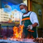 Sprzedawca ulicznego jedzenia grilluje szaszłyki z mięsa na ulicy