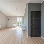 Puste jasne pomieszczenie z drewnianą podłogą i dużymi oknami