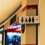 Tabliczka toalet w pasażu z oznaczeniem łazienki dostępnej dla osób z niepełnosp